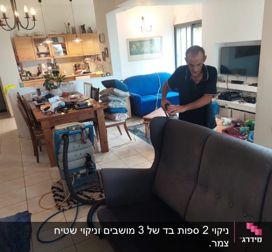 אדם מנקה ספה עם מכונת ניקוי בבית